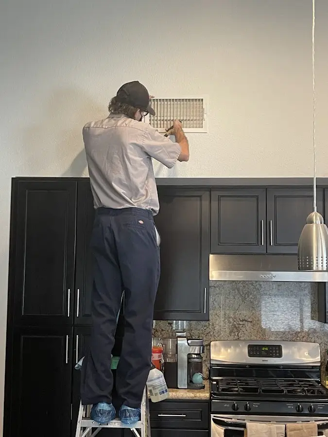 Technician inspecting an air vent during HVAC service in Gladstone